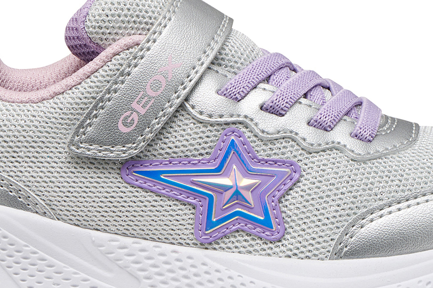 A girls trainer by Geox, style Sprintye in silver/lilac with velcro strap and elastic laces, star design on side, silver detail on heel and toe and white sole. Zoomed view of star detail