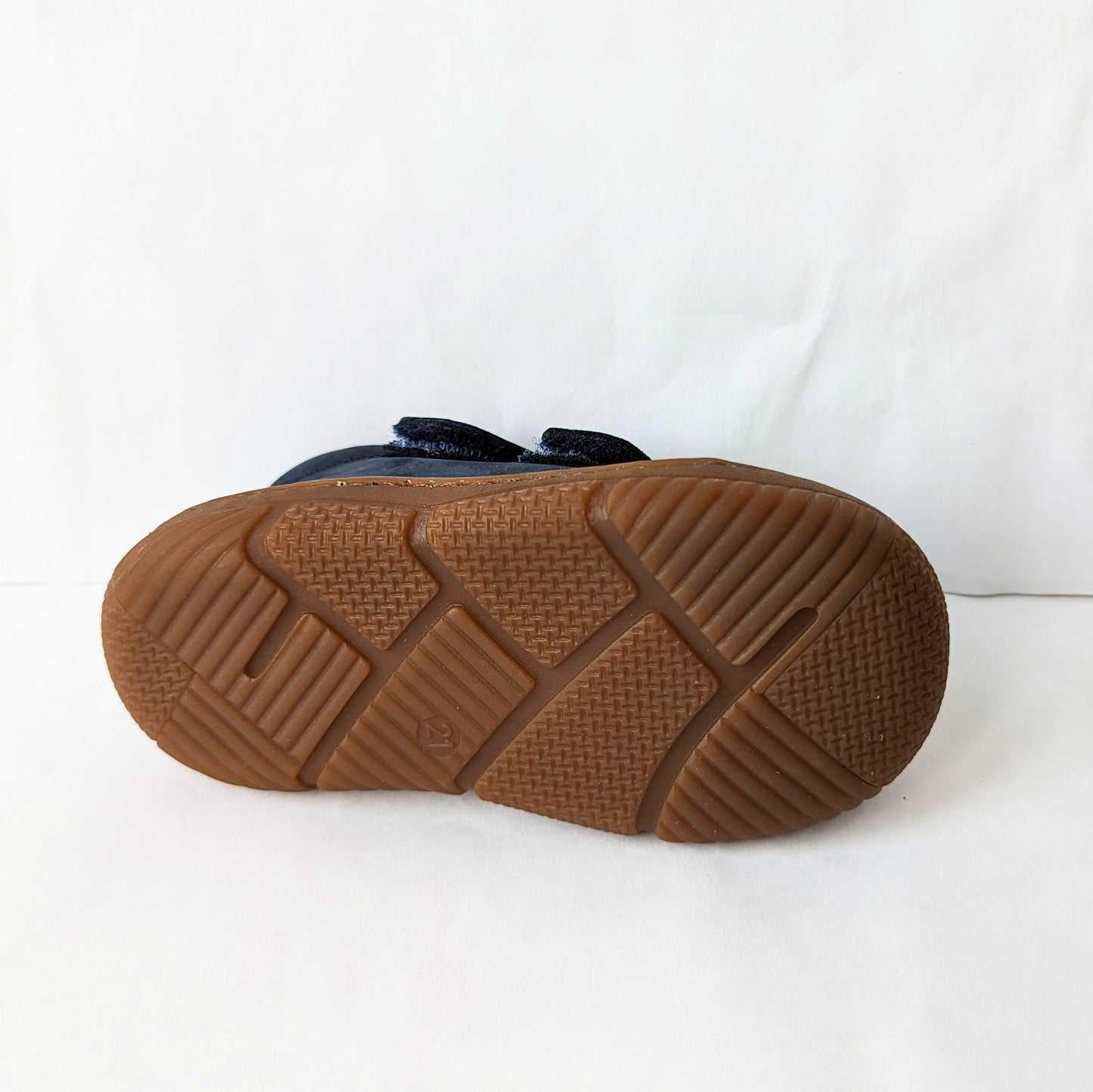 A boys ankle boot by Bopy, style Jameco, in navy nubuck with toe bumper and double velcro fastening. View of brown sole.