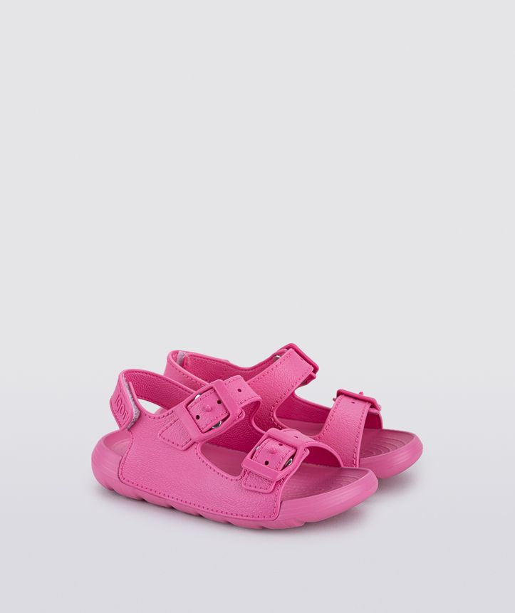 A girls sling back rubber shoe by Igor, style Maui in fucsia with two buckle straps and velcro heel fastening. Angled view.