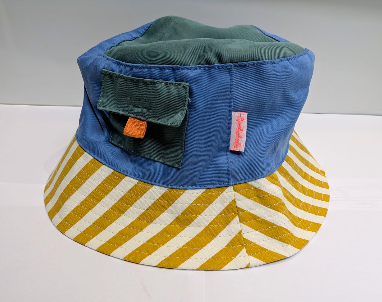 Blue and green bucket hat by Rockahula with a yellow and white striped brim on a white background