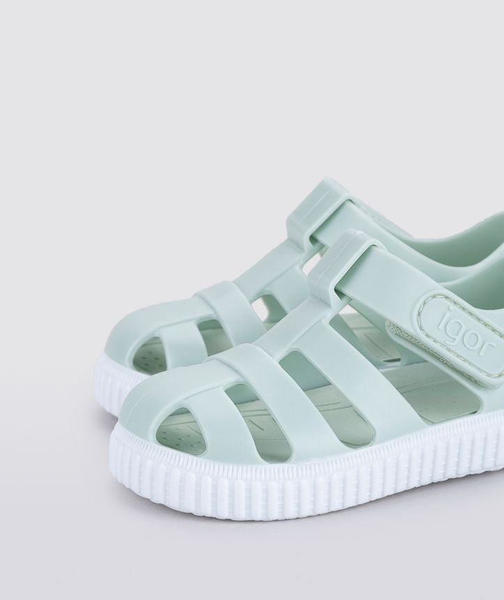 A unisex Jelly shoe by Igor, style Nico in mint green with a white sole, velcro fastening. Left angled view of a pair.