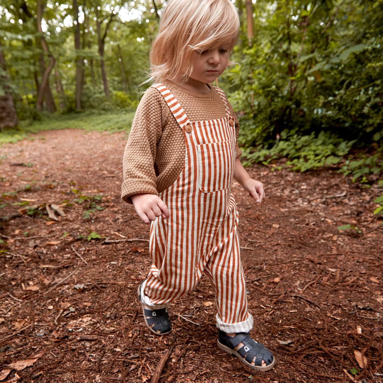 A Little boy walking in the woods wearing boys Navy leather sandal by Start Rite,style Dino, with\ velcro fastening.