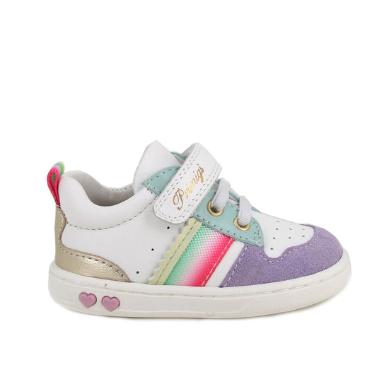 A girls casual trainer by Primigi, style Baby Like in white/iris with elastic laces and velcro strap. Rainbow stripe detail onside purple toe bumper pattern, and metallic design on heel. Two small pink love hearts on white sole. Right side view