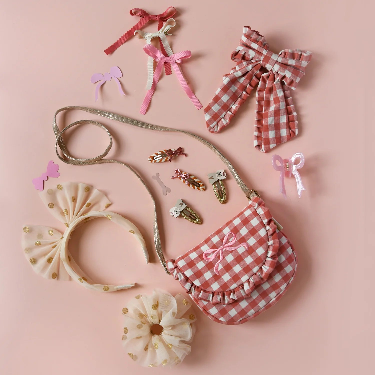 Collection of children's hair accessories by Rockahula including bows and a pink and white gingham bag on a pink background