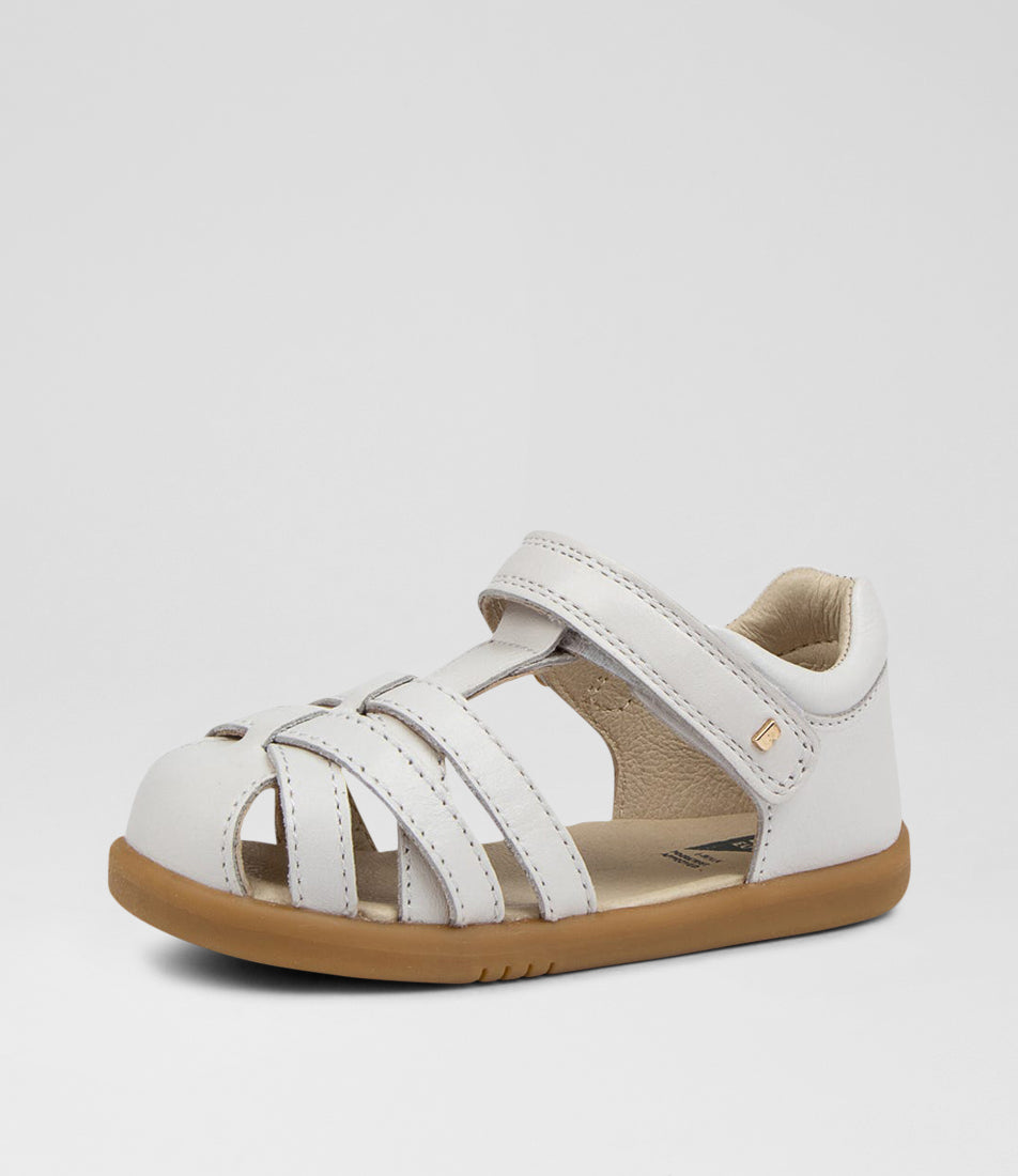 A unisex sandal by Bobux, style Cross Jump in white with velcro strap and light brown sole. Angled side view