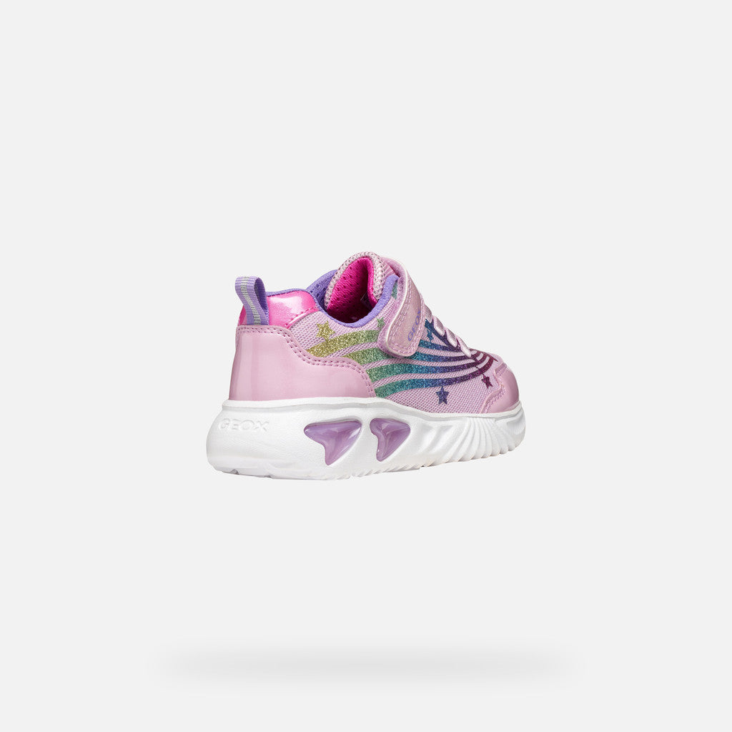 A pink girls trainer by Skechers, style Assister, in pink/multicolour with glittery rainbow and star design, velcro strap and pink laces. Angled right back view