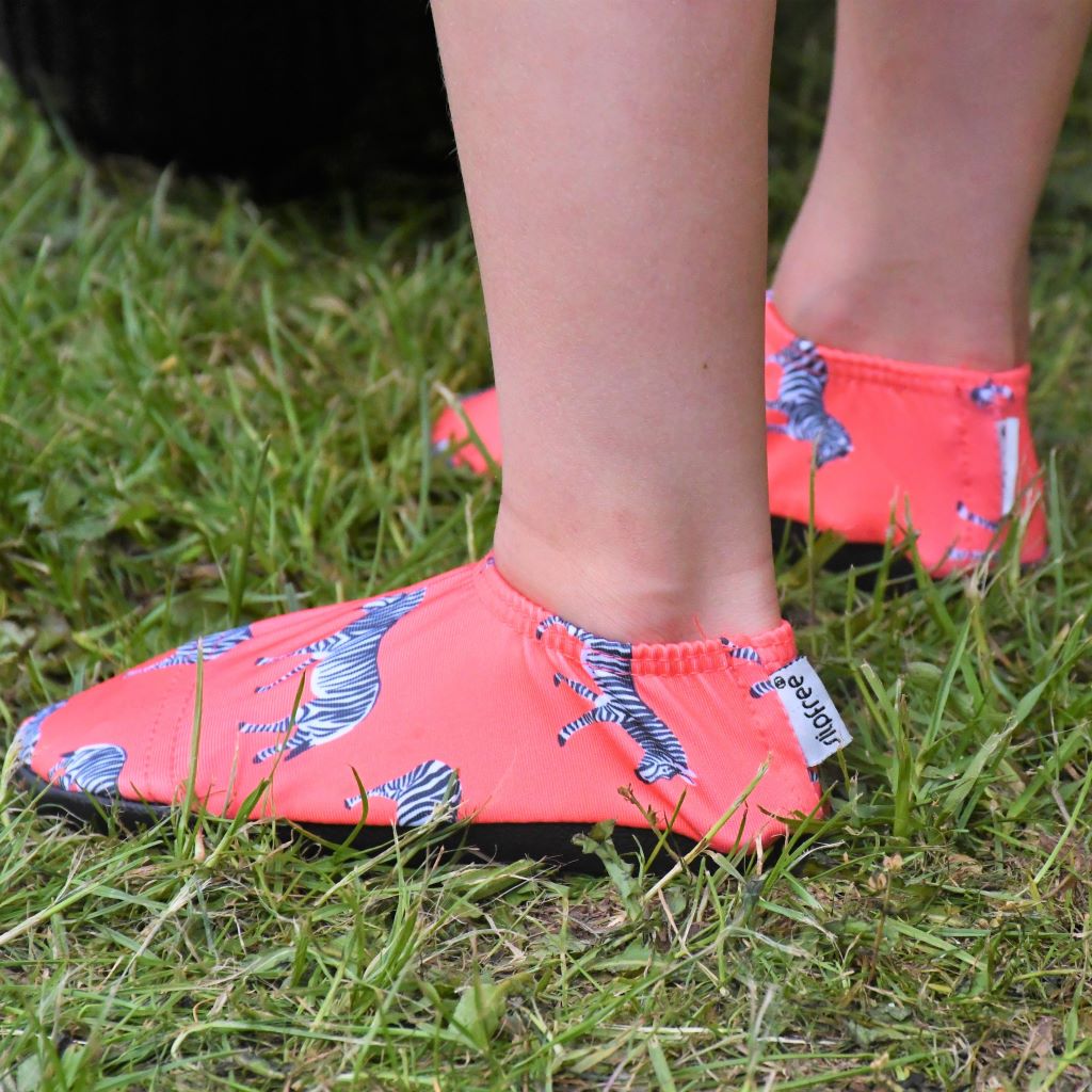 A unisex non slip swim shoe by Slipfree, style Grevy, in coral with Zebra print. Lifestyle image.