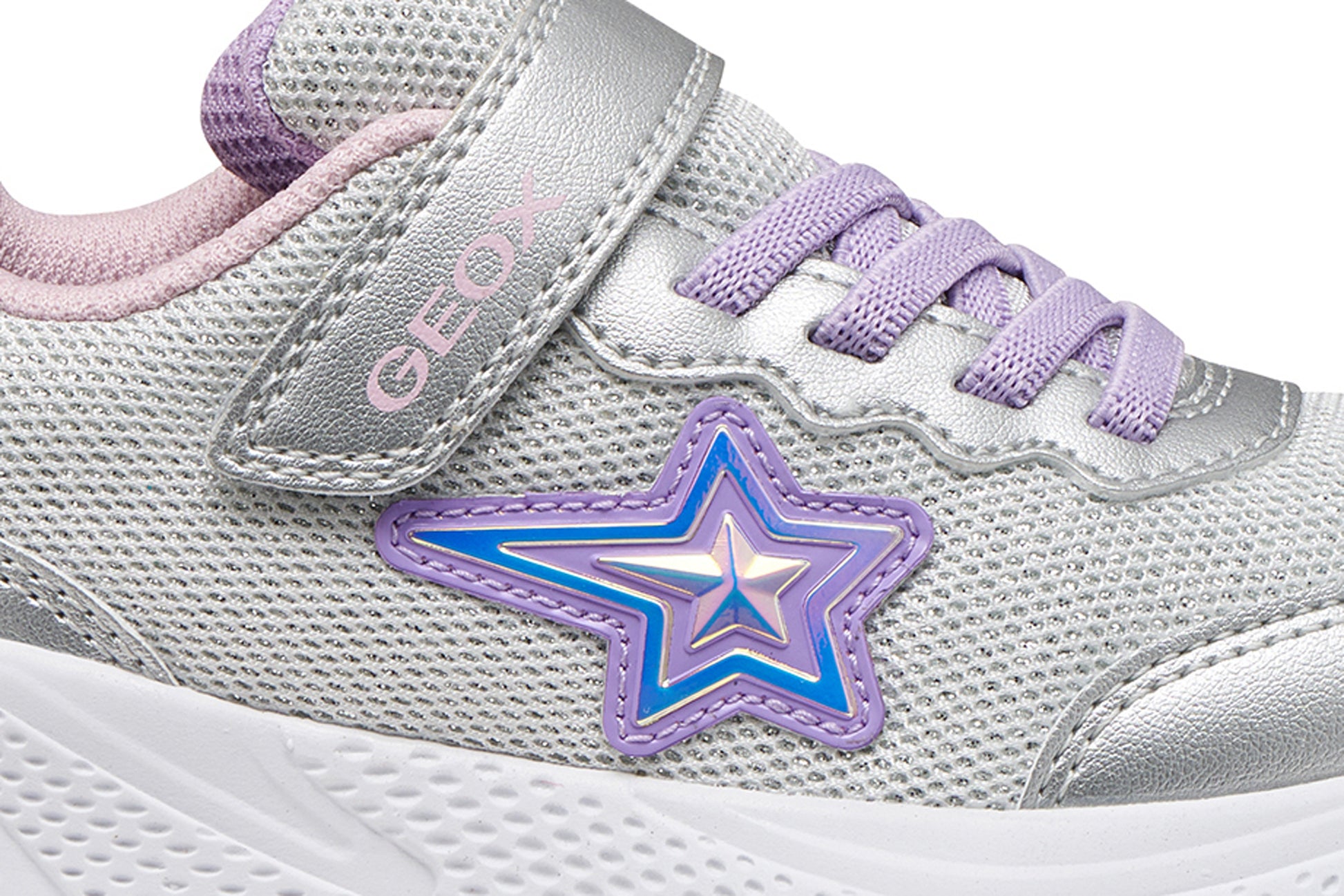 A girls trainer by Geox, style Sprintye in silver/lilac with velcro strap and elastic laces, star design on side, silver detail on heel and toe and white sole. Zoomed view of star detail