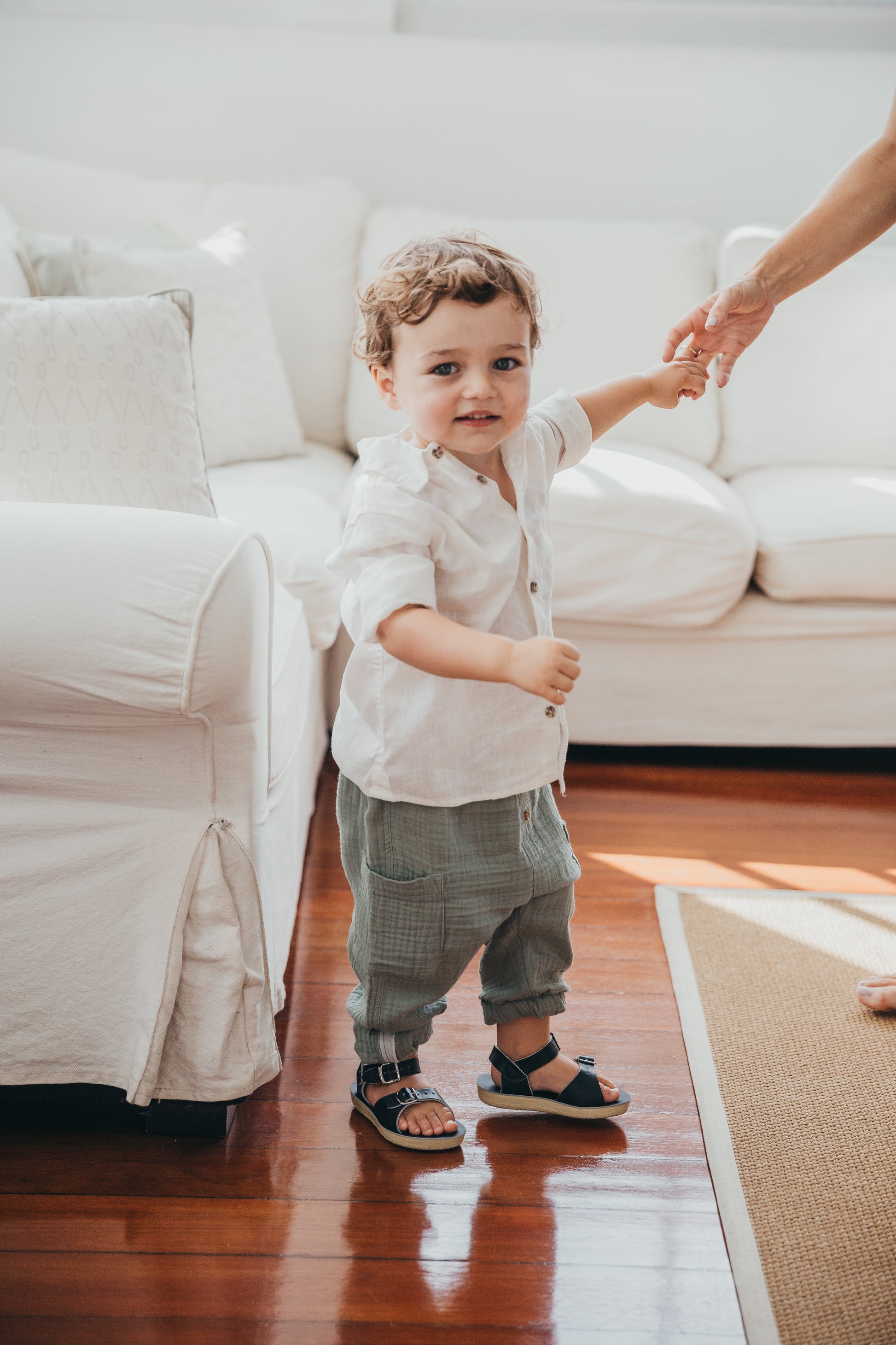 A unisex sandal by Salt Water Sandals in navy with double buckle fastening across the instep and around the ankle. Open Toe and Sling-back. Lifestyle of little boy in livingroom..