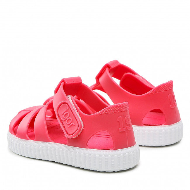 A pair of unisex closed toe jelly shoes by Igor, style Nico, in red and white with velcro fastening.  Angled view of left side.