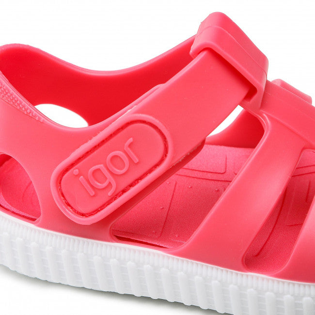 A unisex closed toe jelly shoes by Igor, style Nico, in red and white with velcro fastening. Close up of Igor logo.