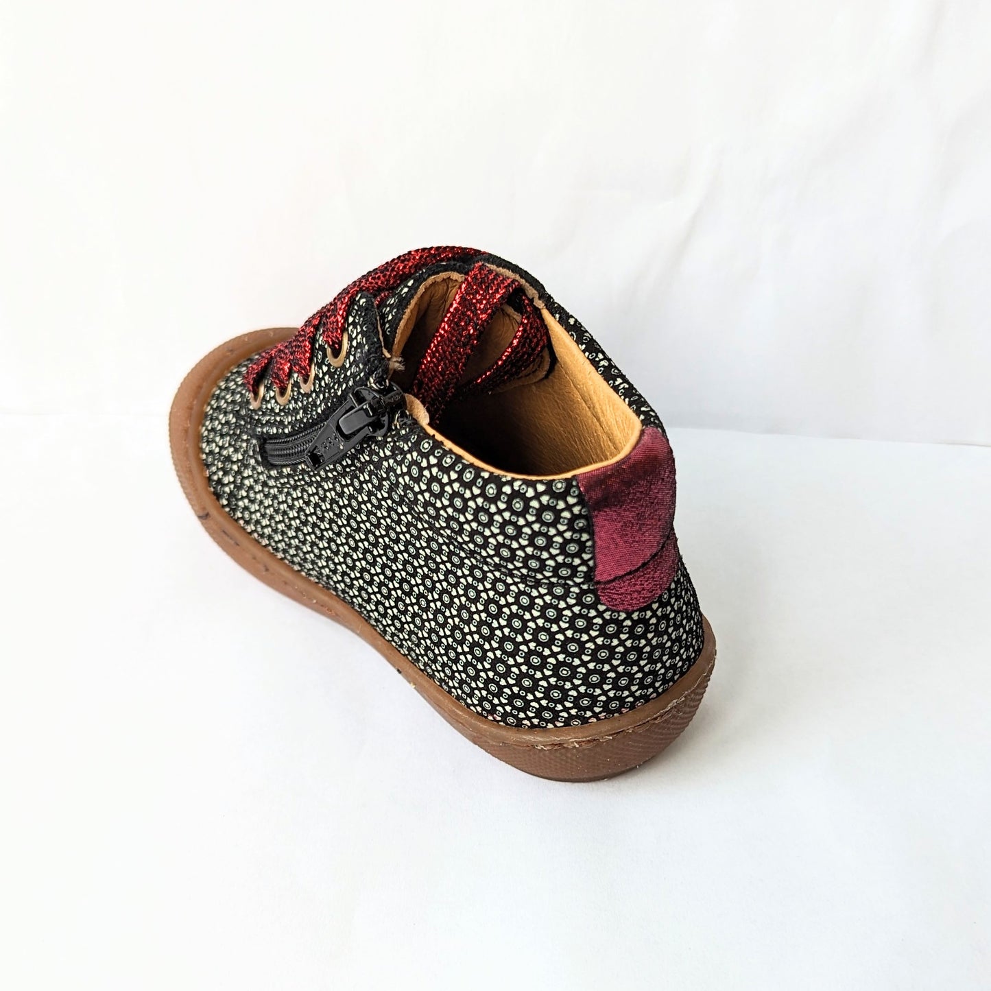 A girls ankle boot by Bopy, style Jolila, in black/silver print nubuck with toe bumper and zip/ bordeaux glitter lace fastening.  Angled back view.