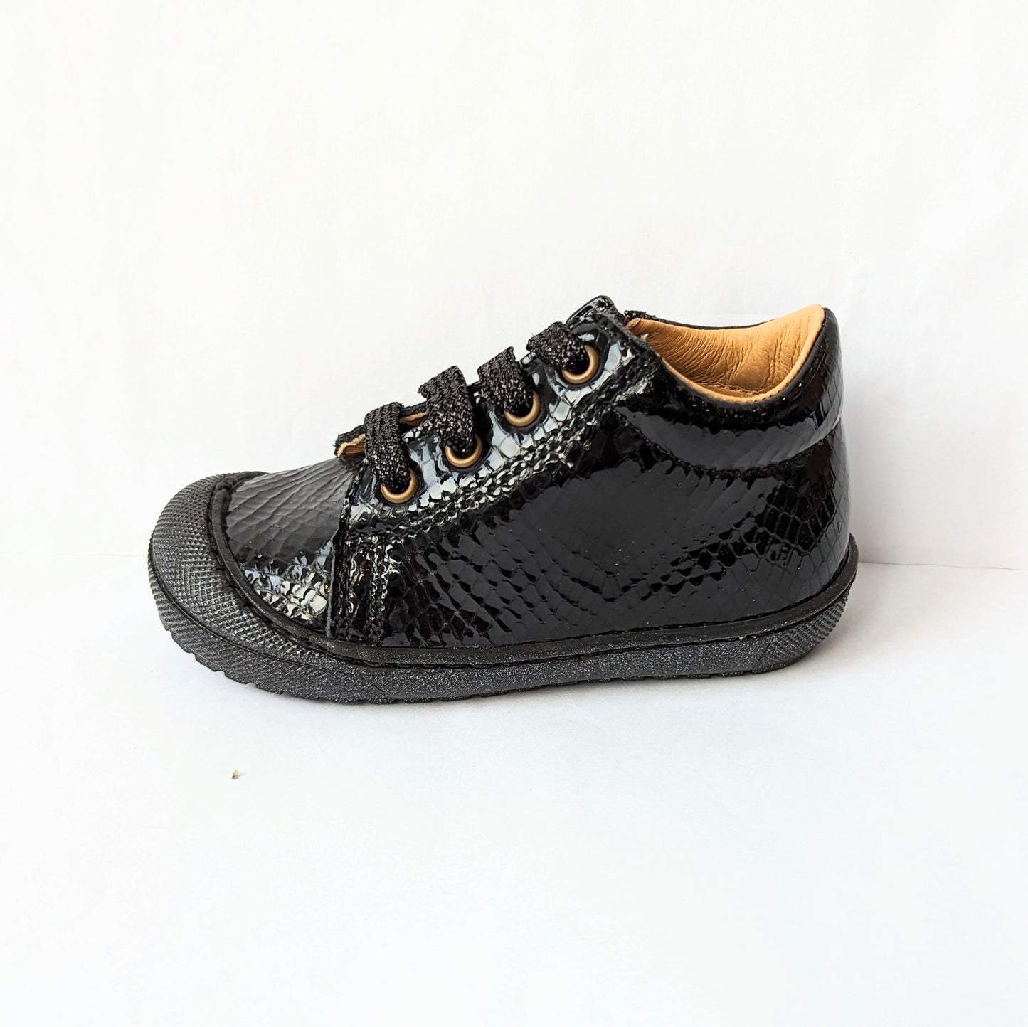 A girls ankle boot by Bopy, style Joseva, in black patent leather croc with toe bumper and zip/glitter lace fastening. Left side view.