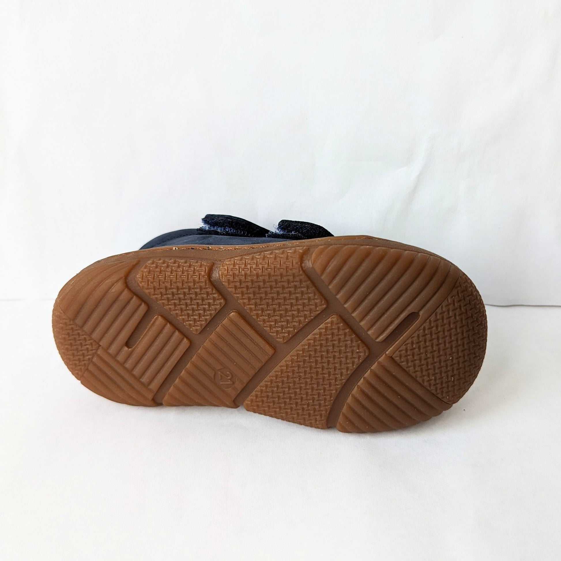 A boys ankle boot by Bopy, style Jameco, in navy nubuck with toe bumper and double velcro fastening. View of brown sole.
