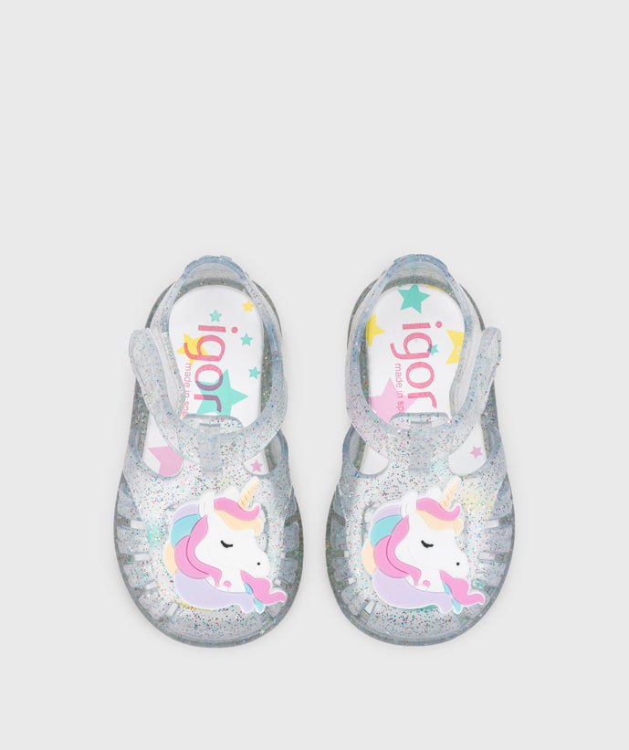 A girls jelly sandal by Igor, style Unicornio in transparent/multi/glitter with velcro strap and unicorn design on front. Top view of pair
