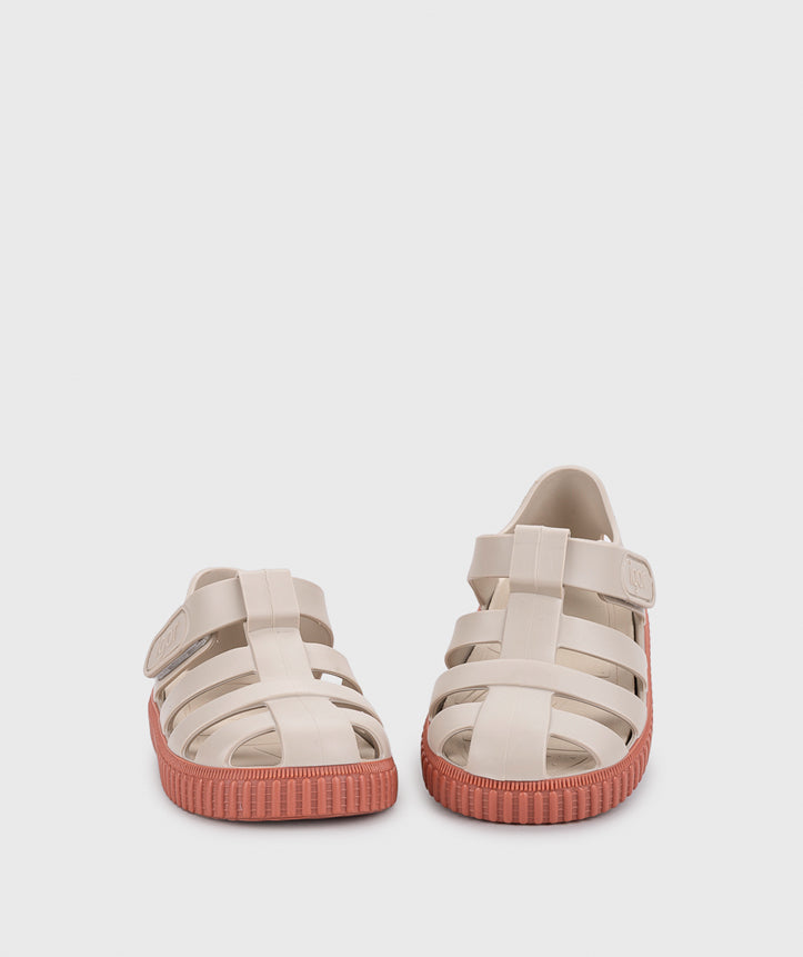 A girls sandal by Igor, style Nico in sand/terracota with velcro strap and pink sole. Front view of pair with one slightly elevated