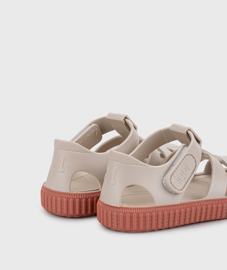 A girls sandal by Igor, style Nico in sand/terracota with velcro strap and pink sole. Zoomed angled back view of pair