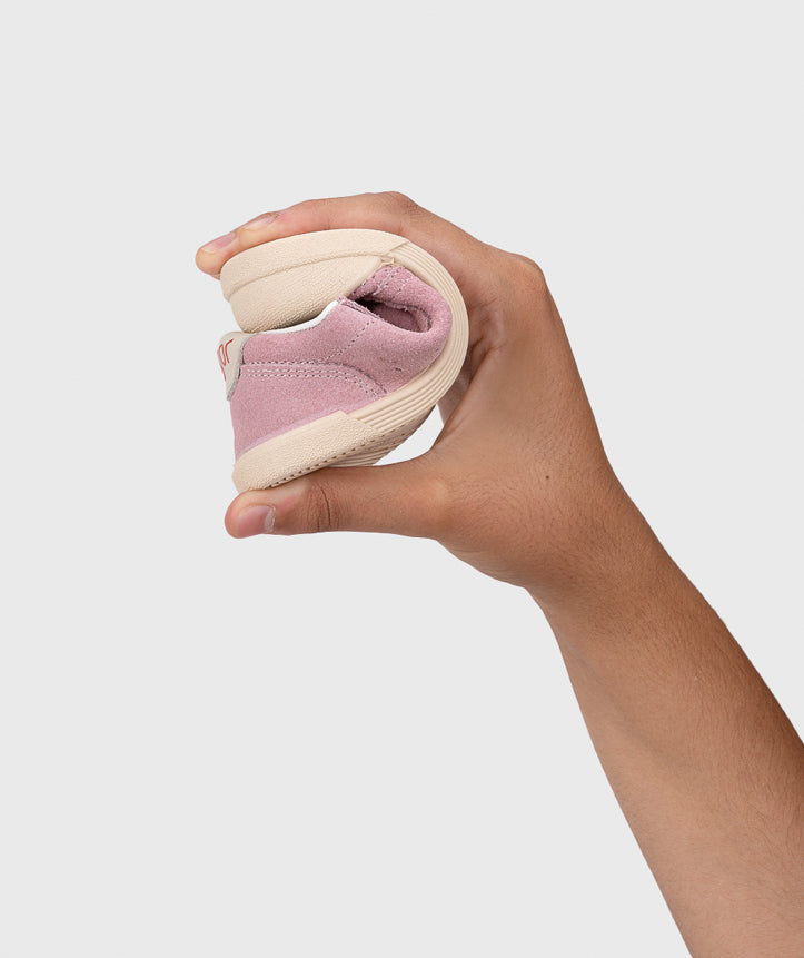 A girls casual shoe by Igor, style Tennis Fresh in Rosa with two velcro straps and toe and heel bumpers. Image of hand bending the shoe fully