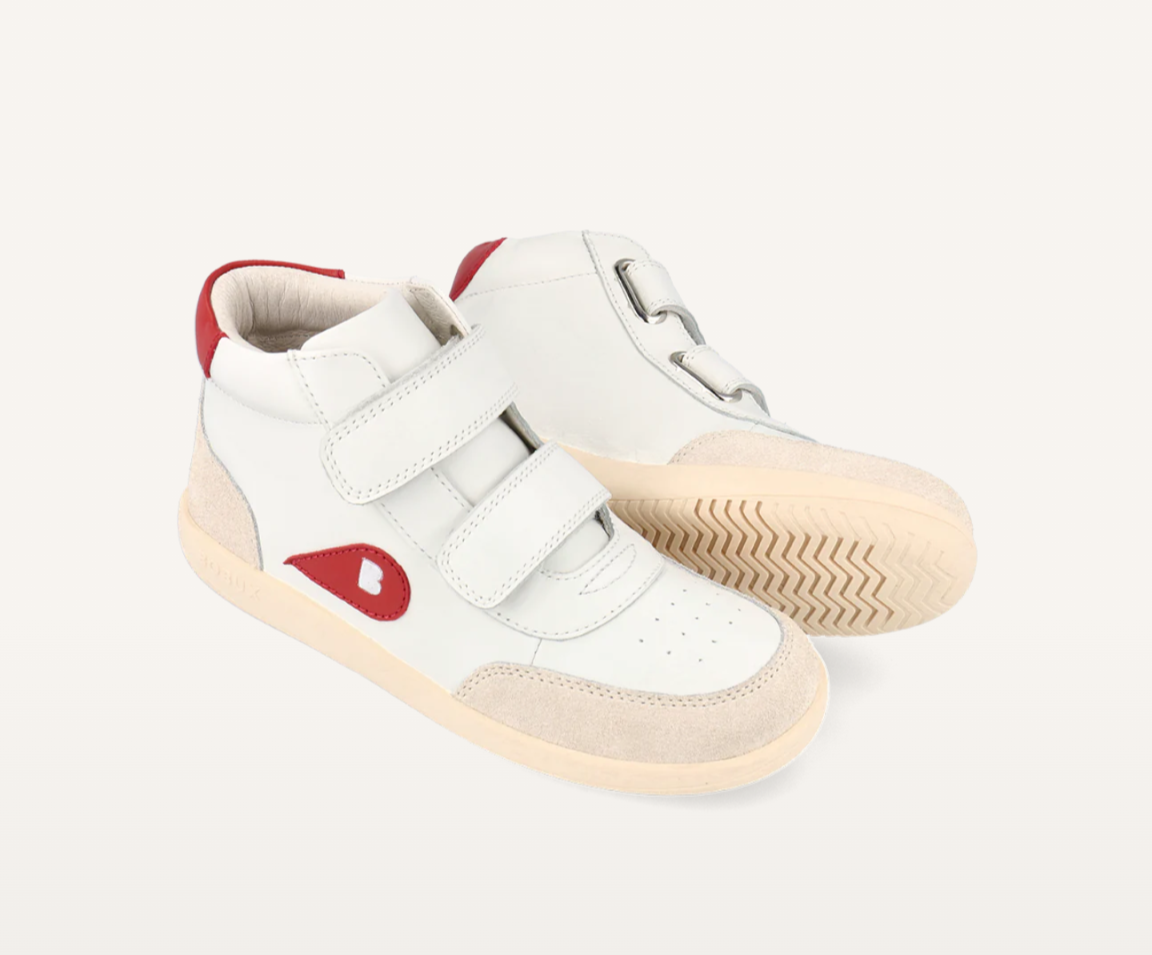 A pair of unisex high top casual boot by Bobux, style Champ, in white with nude and red trim and double velcro fastening. Angled right side view.