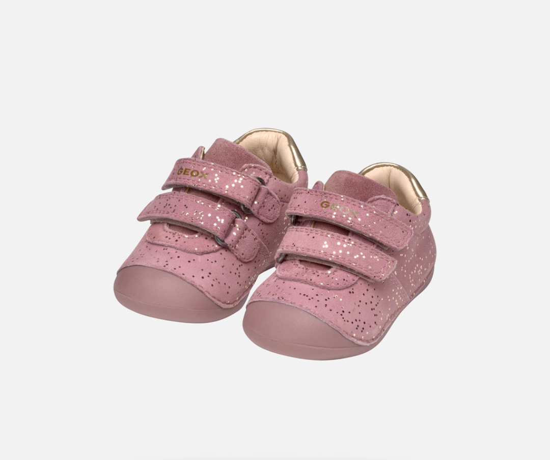 A girls pre walkers by Geox, style B Tutim Girl, in pink nubuck with gold splash print and trim. Double velcro fastening. Angled view of a pair.