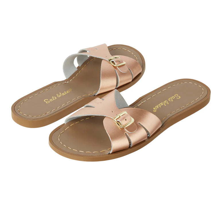 A Slide sandal by Salt Water Sandals in rose gold with single buckle fastening across the instep. Open toe and open back. Side by side view.