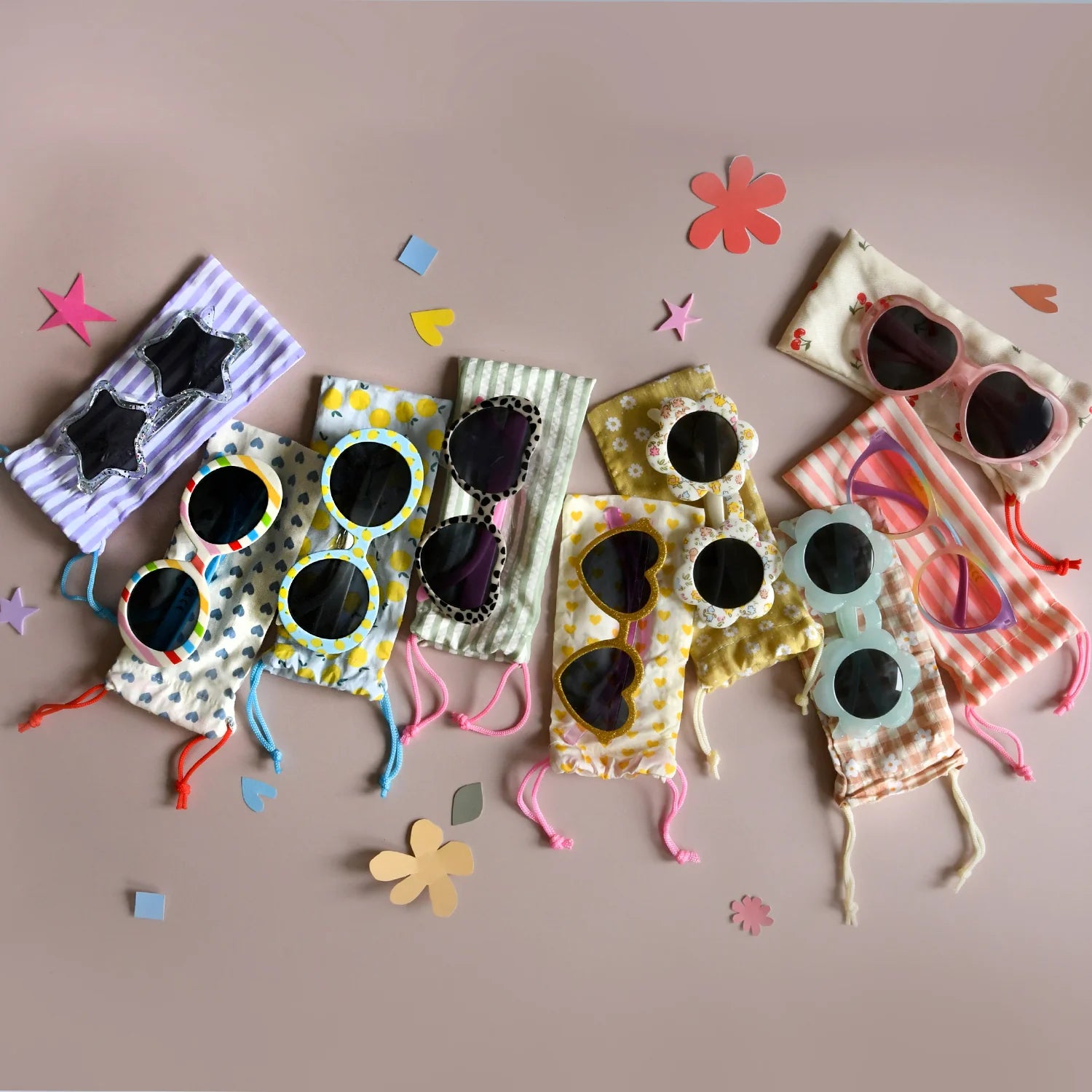 A selection of colourful sunglasses and matching sleeves by Rockahula on a light pink background with confetti