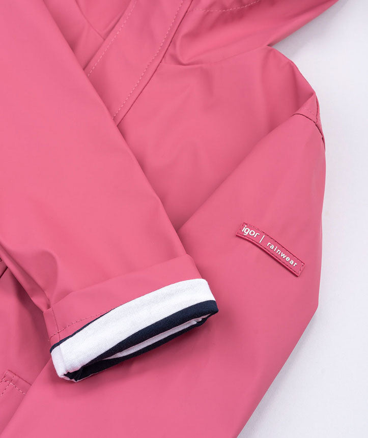 A girls hooded rain coat by Igor, style Euri, in pink with pockets and navy and white stripe lining. Close up of sleeve and branding.