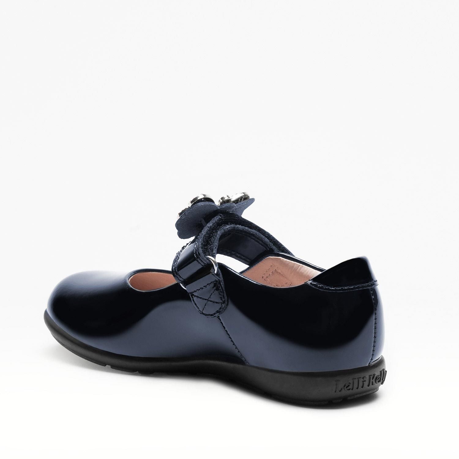A girls Mary-Jane school shoe by Lelli Kelly, style LKSO8641 Luna 2 in Navy patent leather with velcro fastening and detachable multi coloured embellished butterfly. Angled view of left side..