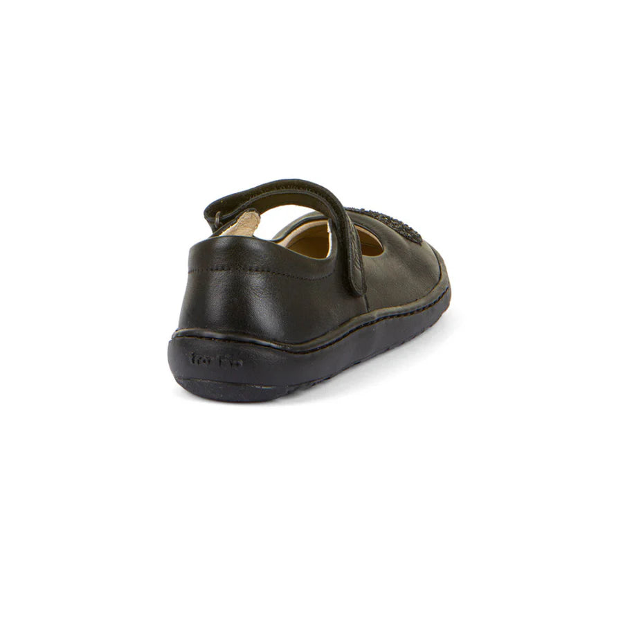 A girls Mary Jane  school shoe by Froddo, style Nina H 3140191, in black leather with glitter heart to front upper and velcro fastening.  Angled back view.