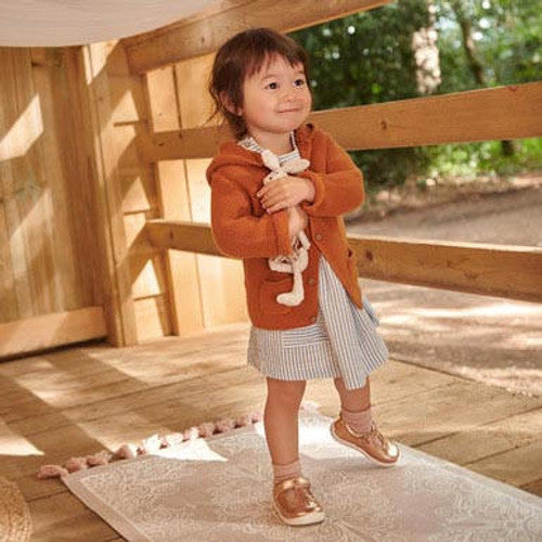A little girl wearing a pair of Start Puzzle T-Bar shoes in Rose Gold leather.