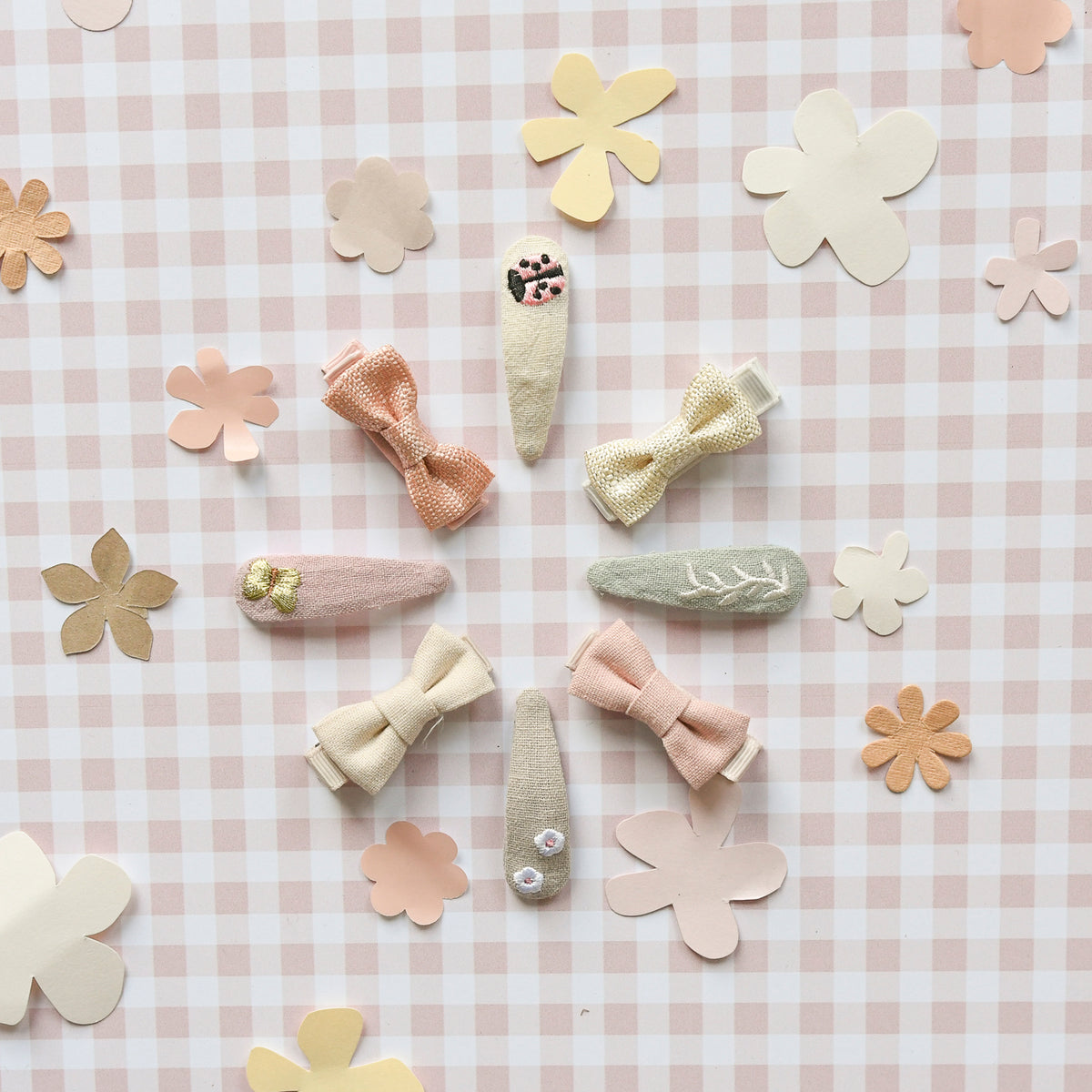 Set of pink, grey and beige hair clips by Rockahula on a checkered background with flower decorations