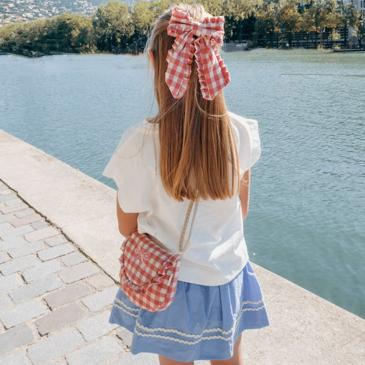 Pink gingham bow hair clip by Rckahula worn by girl with long hair.