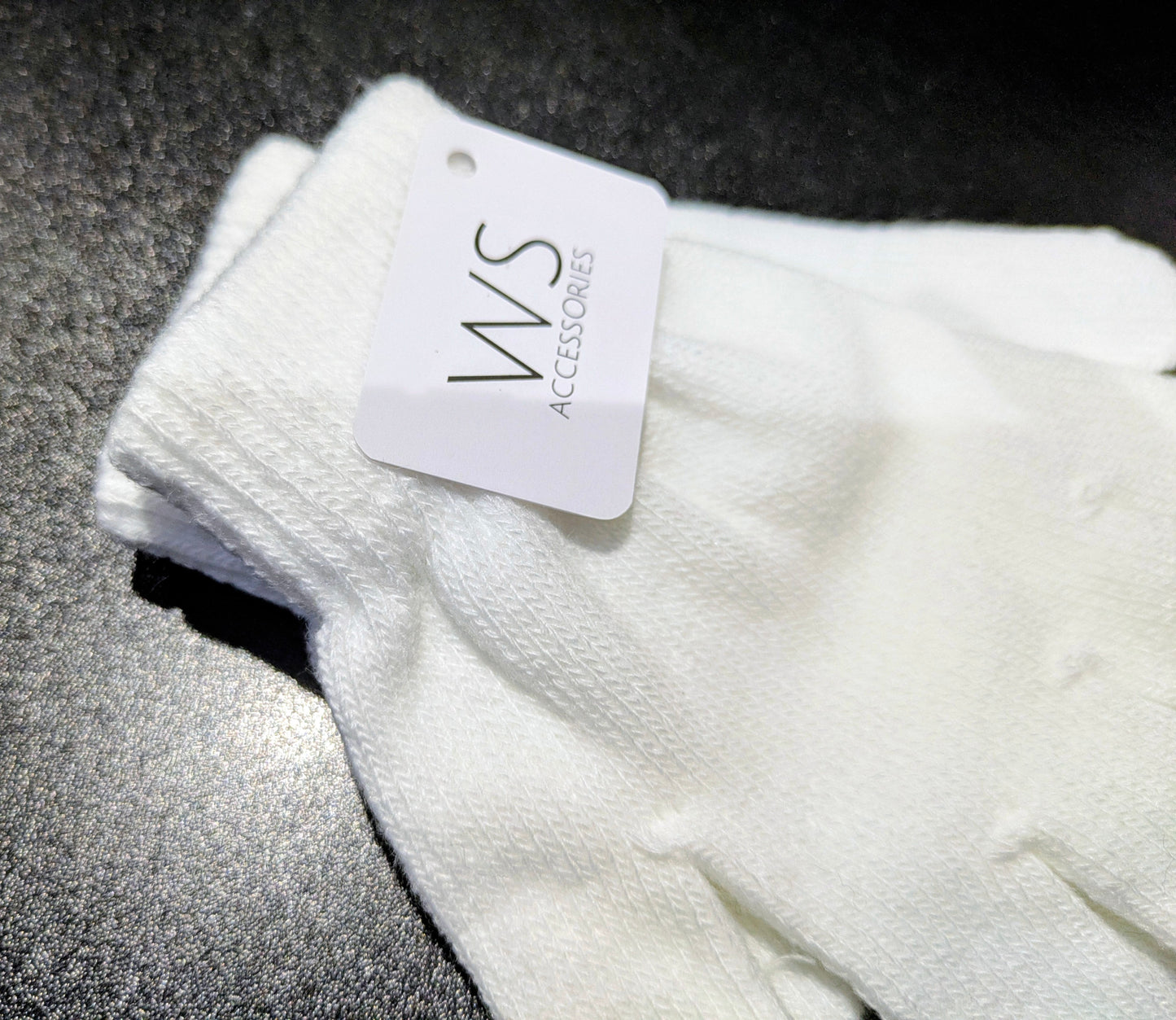 White WS Accessories glove with a brand tag on a grey background. Close up.