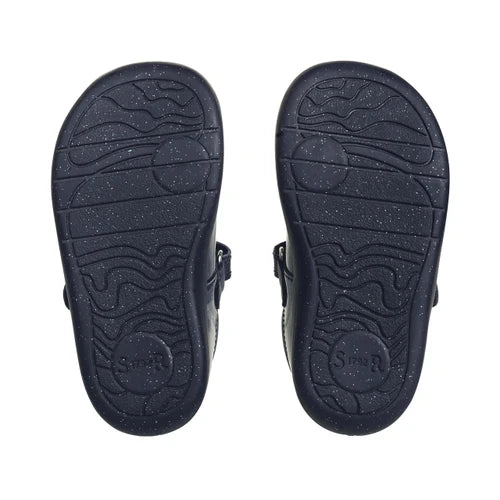 A girls t-bar shoe by StartRite, style Puzzle in patent navy, with flower design on the front and glitter in a black sole. View of soles of pair