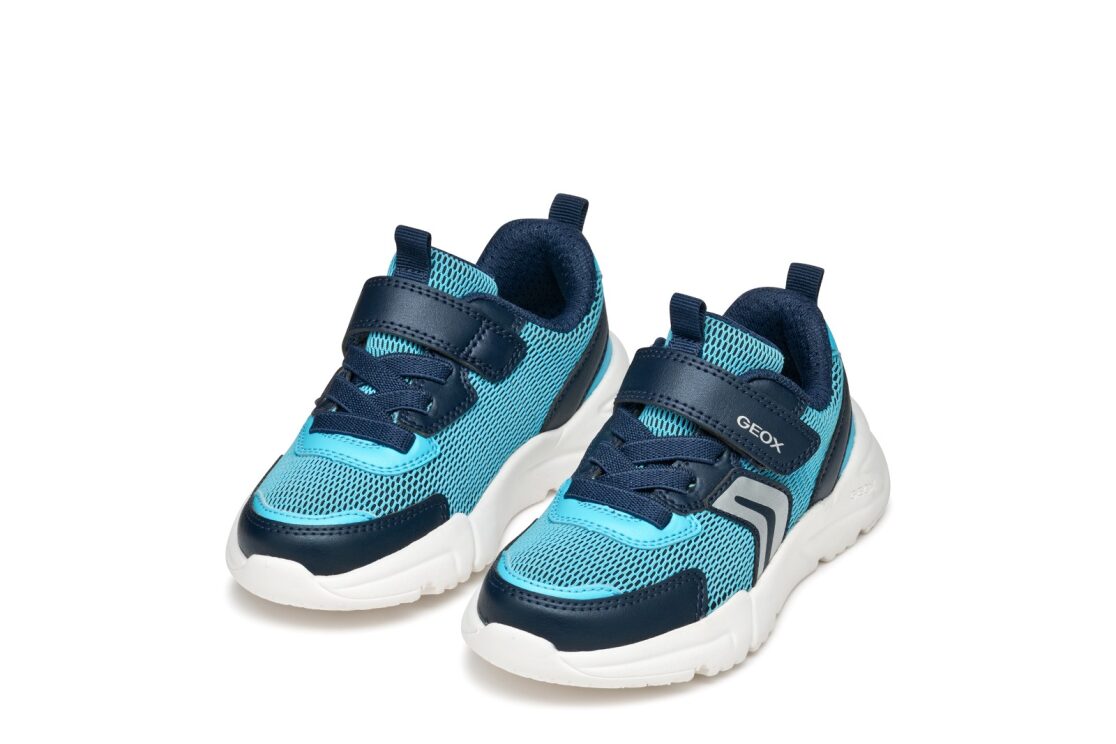 A boys trainer by Geox, style J Loftus, in sky/ navy, velcro fastening with elastic laces. Angled view of a pair.