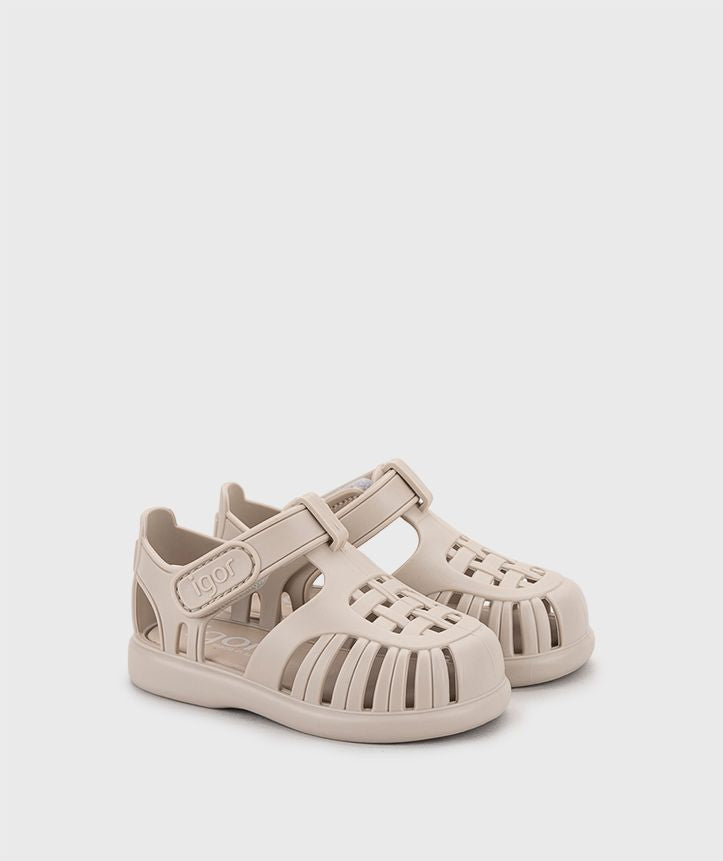 A child's closed toe unisex jelly sandal by Igor, style Tobby Solid, in cream  with velcro fastening. Angled right side view of a pair.